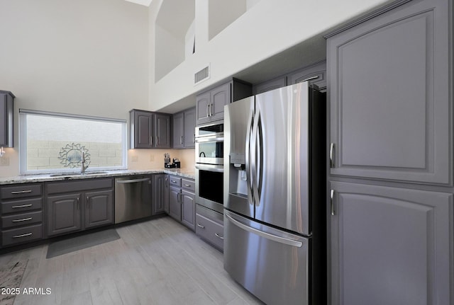 kitchen featuring gray cabinets, light stone countertops, sink, and stainless steel appliances