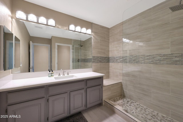 bathroom featuring a tile shower and vanity