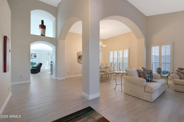 living room featuring light hardwood / wood-style floors, a high ceiling, and an inviting chandelier