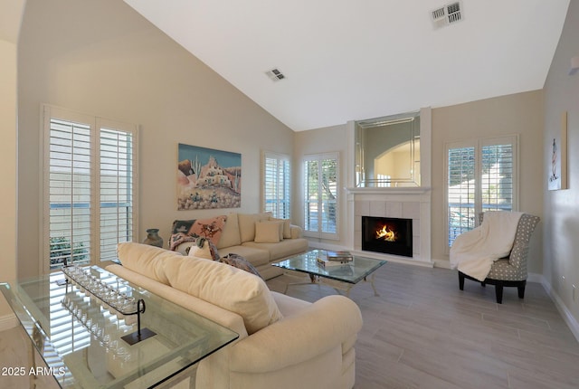 living room with high vaulted ceiling, wood-type flooring, and a tile fireplace