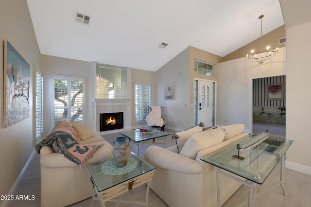 living room with an inviting chandelier, vaulted ceiling, and a tiled fireplace