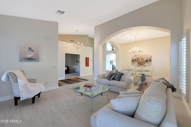 living room featuring light hardwood / wood-style flooring, vaulted ceiling, and a notable chandelier