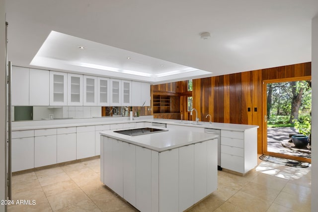 kitchen with kitchen peninsula, black electric cooktop, sink, white cabinets, and a center island