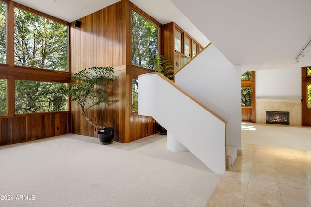 stairs with carpet flooring, wood walls, plenty of natural light, and a high ceiling