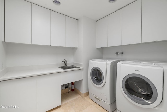 clothes washing area with light tile patterned flooring, cabinets, separate washer and dryer, and sink