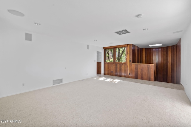 carpeted spare room with wooden walls