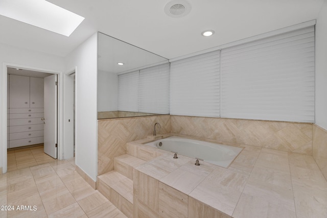 bathroom featuring tile patterned floors, a skylight, and a washtub