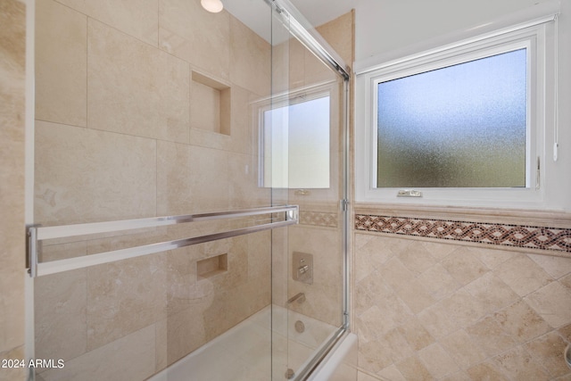 bathroom featuring shower / bath combination with glass door and tile walls