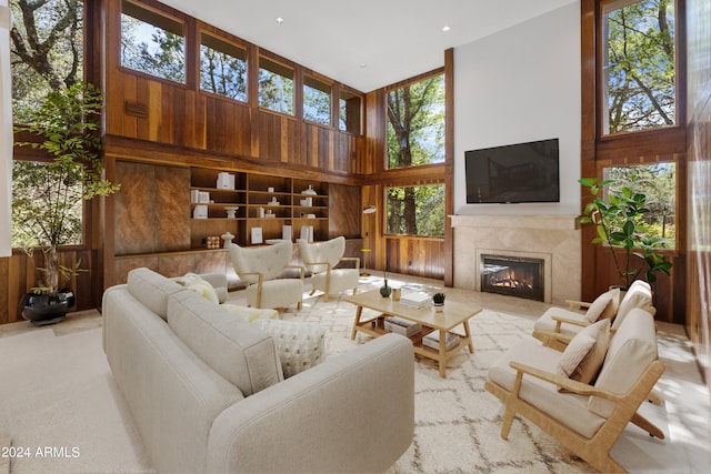 living room featuring wood walls, a healthy amount of sunlight, and a high ceiling