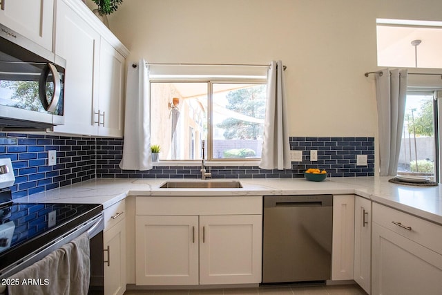 kitchen with white cabinetry, sink, decorative backsplash, and stainless steel appliances