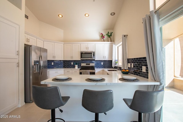 kitchen with sink, white cabinetry, appliances with stainless steel finishes, kitchen peninsula, and decorative backsplash