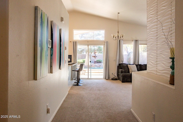 hallway with high vaulted ceiling, a chandelier, and carpet floors