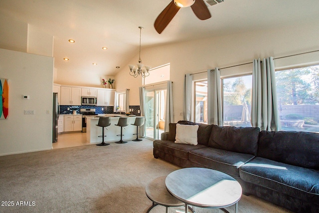 carpeted living room featuring high vaulted ceiling and ceiling fan with notable chandelier