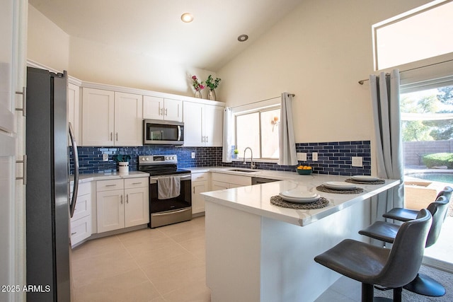 kitchen with sink, a breakfast bar area, appliances with stainless steel finishes, white cabinetry, and kitchen peninsula