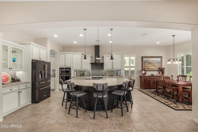 5771 W Cinder Brook Way, Florence, AZ 85132 - kitchen with high end black refrigerator, wall chimney exhaust hood, multiple ovens, backsplash, and plenty of natural light