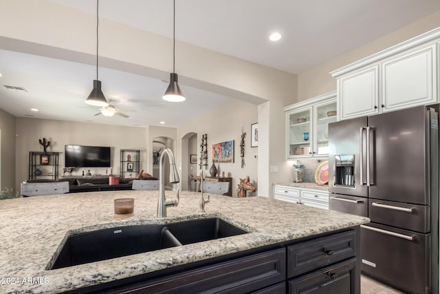 5771 W Cinder Brook Way, Florence, AZ 85132 - kitchen with high end fridge, a sink, arched walkways, white cabinets, and light stone counters
