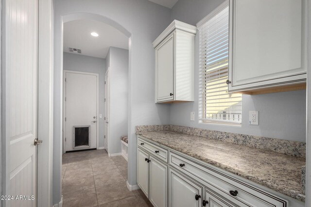 5771 W Cinder Brook Way, Florence, AZ 85132 - kitchen with arched walkways, baseboards, white cabinets, light tile patterned floors, and recessed lighting