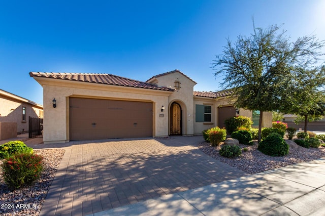 5771 W Cinder Brook Way, Florence, AZ 85132 - mediterranean / spanish-style home with stucco siding, an attached garage, decorative driveway, and a tiled roof