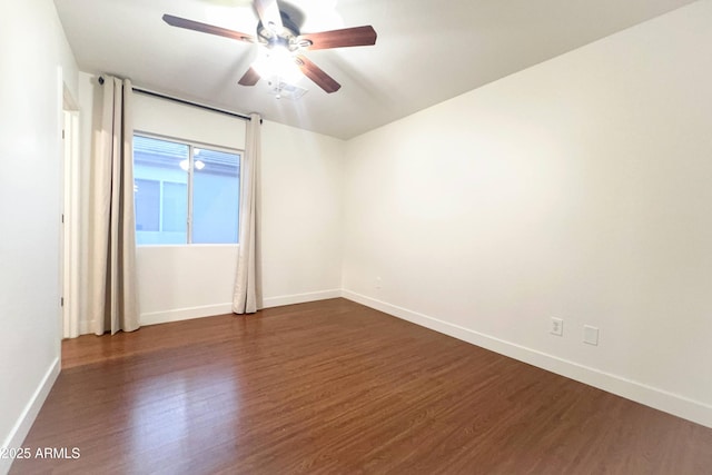 unfurnished room with dark wood-type flooring, a ceiling fan, and baseboards