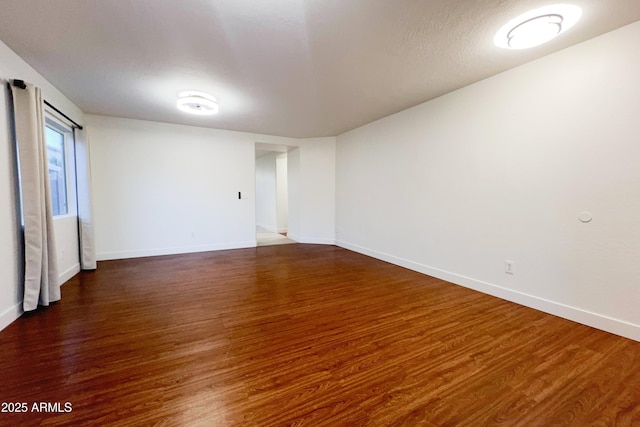 unfurnished room featuring dark wood-type flooring and baseboards