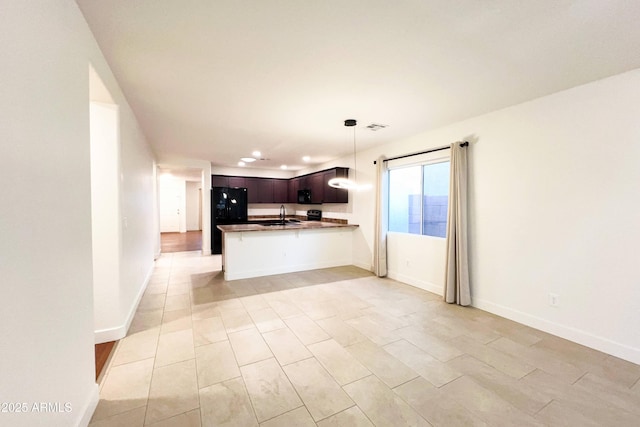 kitchen featuring a sink, freestanding refrigerator, a peninsula, pendant lighting, and open floor plan