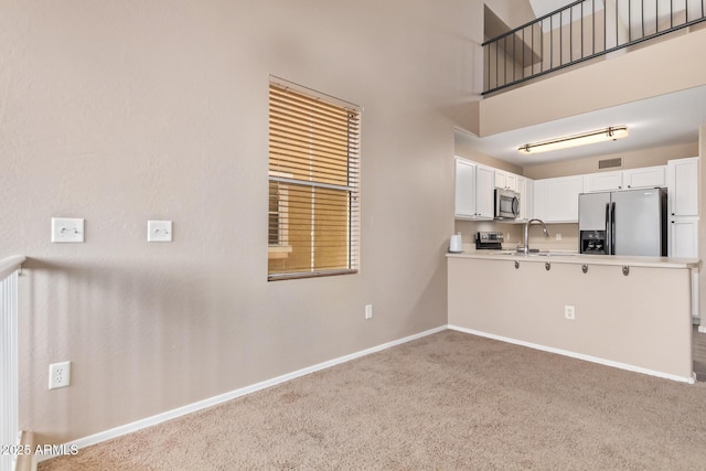 9233 E Neville Ave Unit 1127, Mesa, AZ 85209 - kitchen with appliances with stainless steel finishes, carpet, white cabinetry, light countertops, and a high ceiling