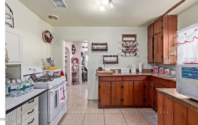 kitchen with white gas stove and light tile patterned floors