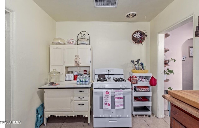 kitchen with white gas range, light tile patterned floors, and white cabinets