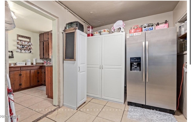 kitchen featuring light tile patterned floors and stainless steel refrigerator with ice dispenser