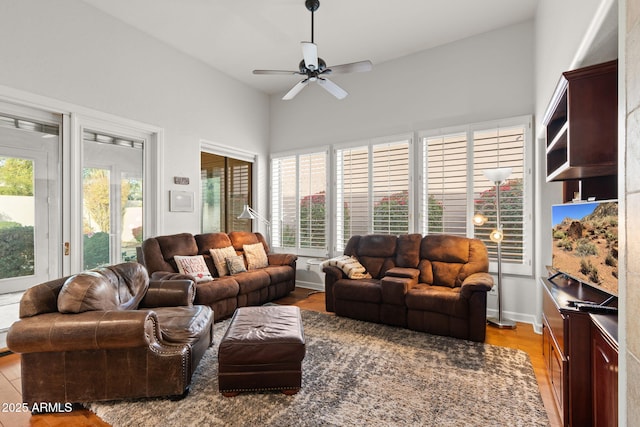 living room with a wealth of natural light, light hardwood / wood-style flooring, ceiling fan, and lofted ceiling