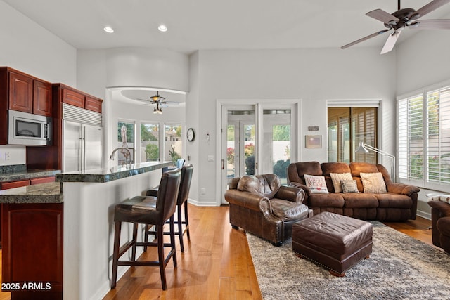 kitchen with a kitchen bar, light wood-type flooring, ceiling fan, sink, and built in appliances