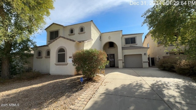 mediterranean / spanish-style house featuring a garage, concrete driveway, and stucco siding