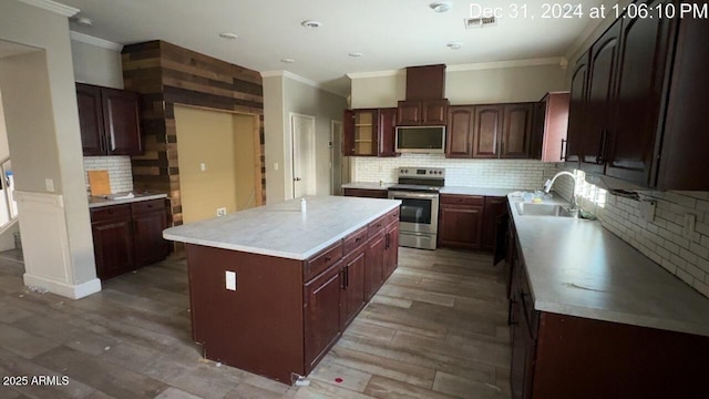 kitchen with light wood-style flooring, a kitchen island, ornamental molding, stainless steel appliances, and a sink