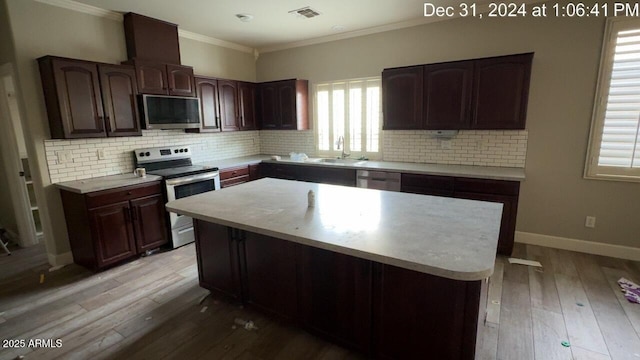 kitchen featuring stainless steel appliances, visible vents, ornamental molding, and light wood finished floors