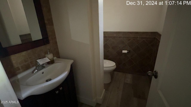 bathroom featuring toilet, tile walls, and vanity