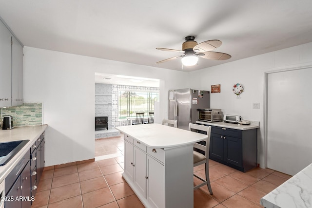 1308 N 66th St, Scottsdale, AZ 85257 - kitchen with freestanding refrigerator, a wood stove, a ceiling fan, light countertops, and light tile patterned floors