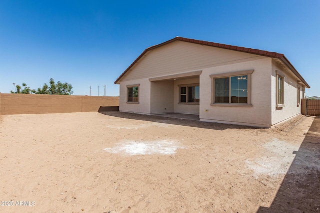 rear view of house with stucco siding and a fenced backyard