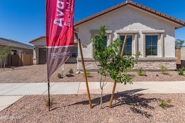 view of front of house with fence, stucco siding, decorative driveway, and a tiled roof