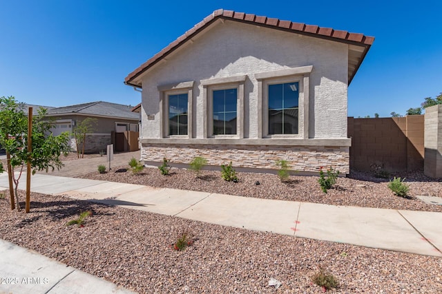 view of front of property with fence, stucco siding, and a tiled roof