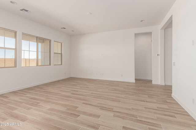 empty room featuring visible vents, light wood-style flooring, and baseboards