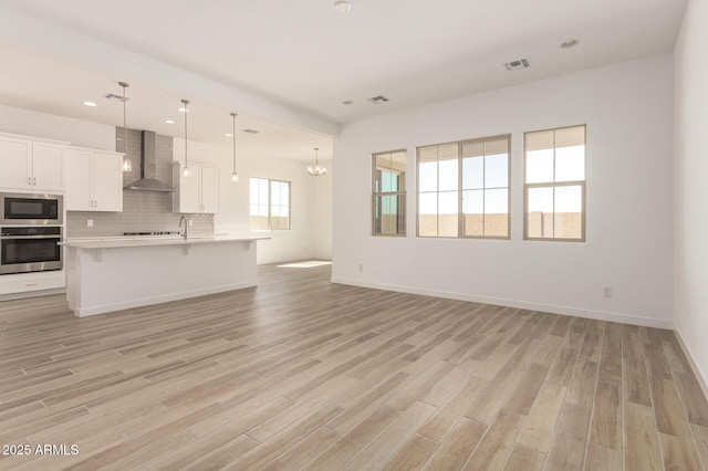 unfurnished living room with recessed lighting, visible vents, baseboards, and light wood-style floors