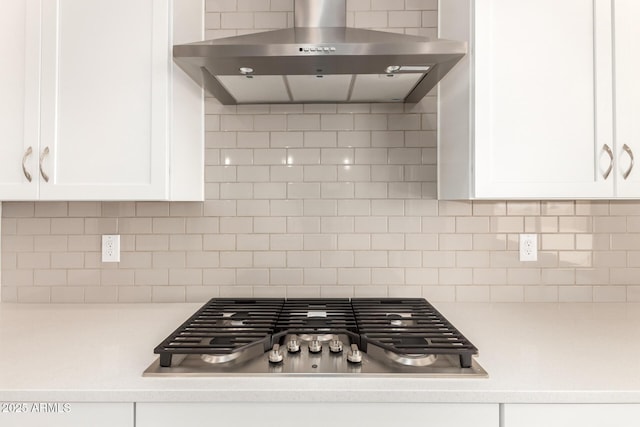 kitchen with white cabinets, stainless steel gas cooktop, wall chimney exhaust hood, and light countertops