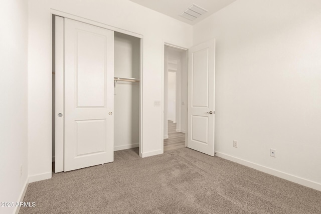 unfurnished bedroom featuring visible vents, a closet, baseboards, and carpet floors