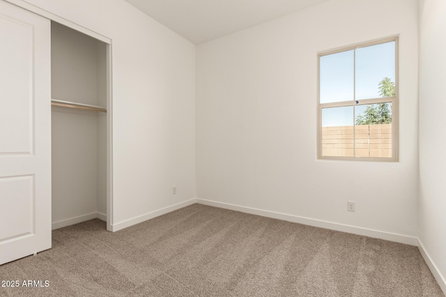 unfurnished bedroom featuring a closet, baseboards, and light carpet