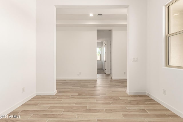 empty room featuring visible vents, light wood-style flooring, and baseboards