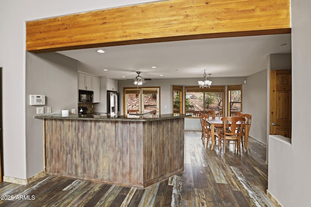 kitchen featuring dark wood-style floors, dark stone countertops, a peninsula, and black microwave