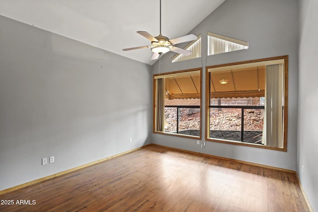 spare room with ceiling fan, baseboards, wood finished floors, and vaulted ceiling