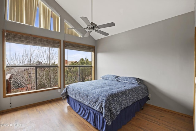 bedroom featuring baseboards, lofted ceiling, wood finished floors, and a ceiling fan