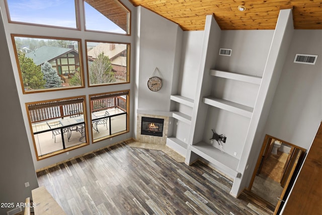 unfurnished living room featuring wood finished floors, built in features, wood ceiling, and visible vents