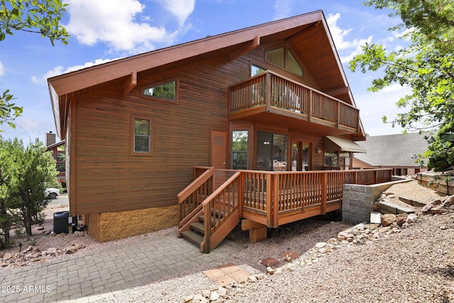 rear view of property featuring a balcony and central AC unit